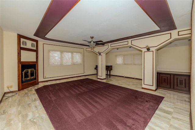 unfurnished living room with a fireplace, baseboards, and ceiling fan