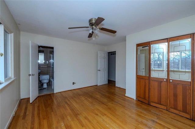 unfurnished bedroom with light wood-style floors, baseboards, and ensuite bathroom