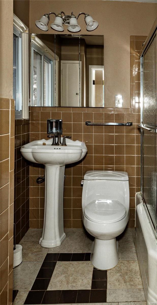 full bath with enclosed tub / shower combo, tile walls, toilet, and tile patterned floors