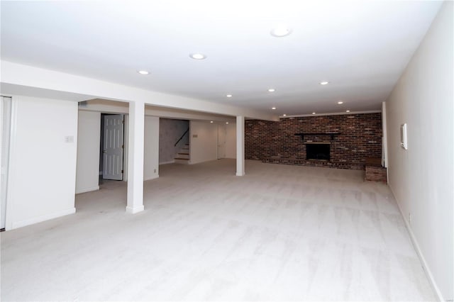 finished below grade area featuring light colored carpet, brick wall, stairs, a fireplace, and recessed lighting