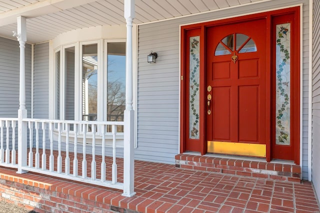 entrance to property featuring brick siding and covered porch