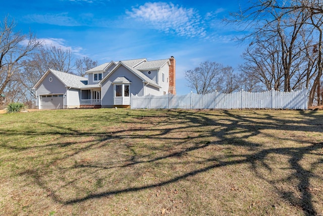 view of front facade with a yard, fence, and a garage