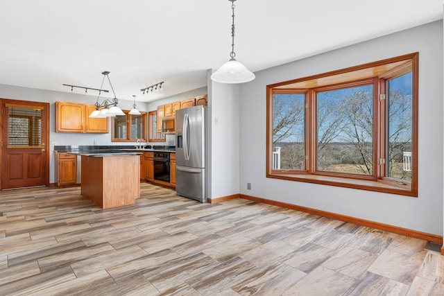 kitchen featuring black oven, stainless steel fridge, a kitchen island, and baseboards