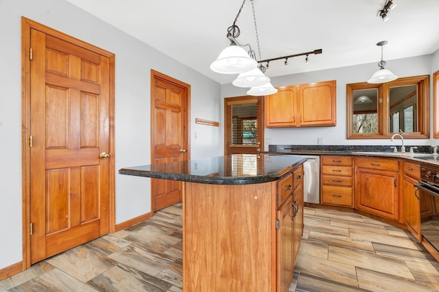 kitchen with dark stone countertops, a sink, a center island, wall oven, and hanging light fixtures