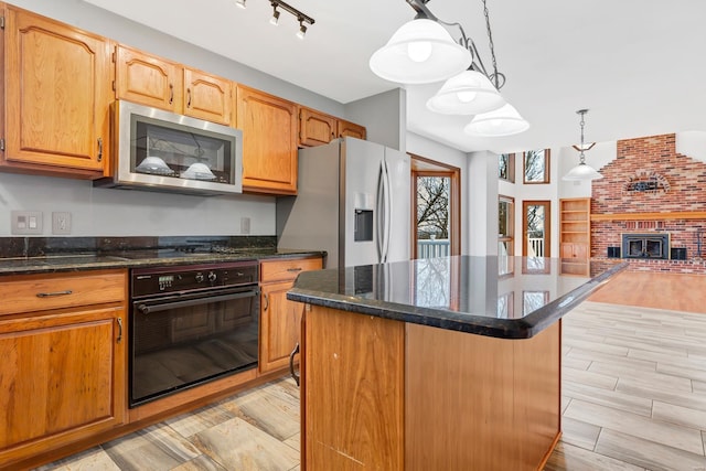 kitchen featuring a center island, wood tiled floor, decorative light fixtures, open floor plan, and black appliances