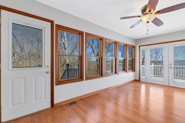 unfurnished sunroom featuring visible vents, a ceiling fan, and french doors