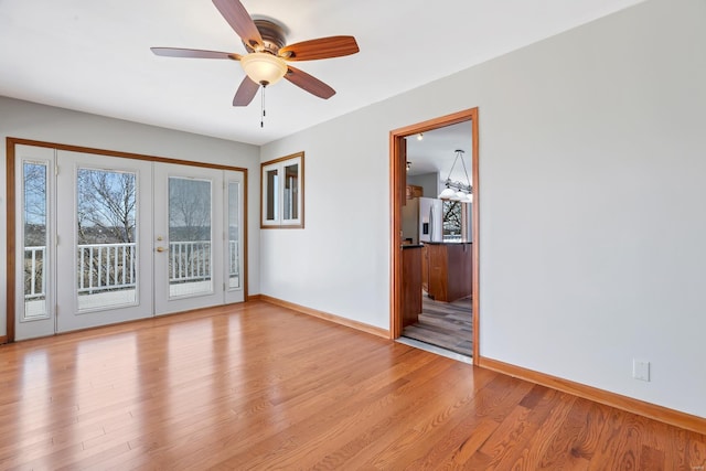 spare room with light wood-style flooring, french doors, a ceiling fan, and baseboards