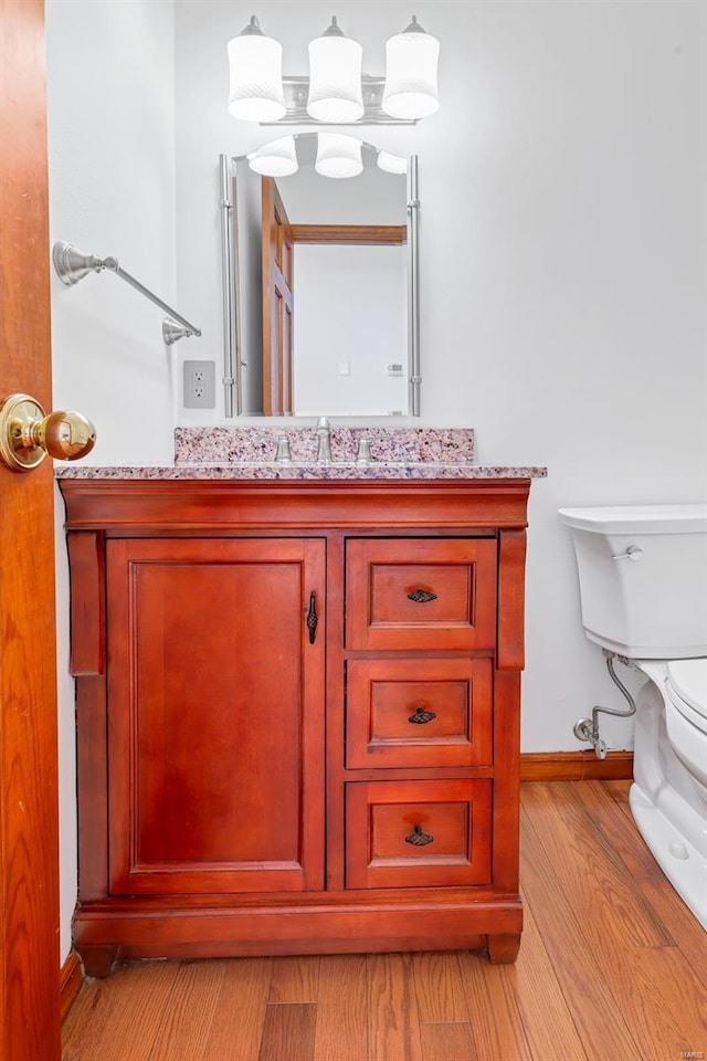 bathroom featuring toilet, vanity, baseboards, and wood finished floors