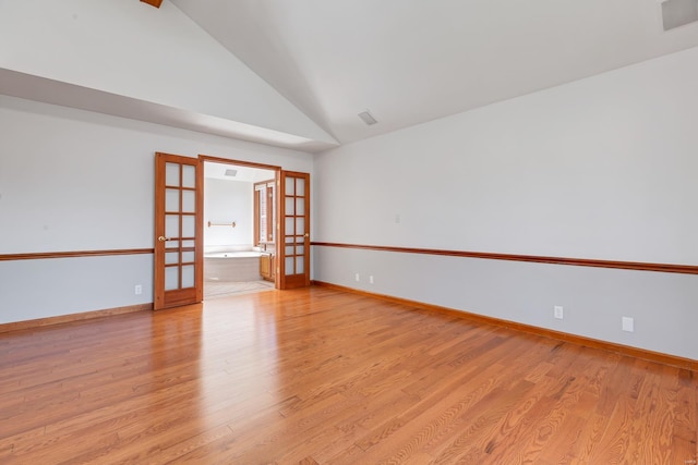 spare room featuring light wood finished floors, french doors, high vaulted ceiling, and baseboards