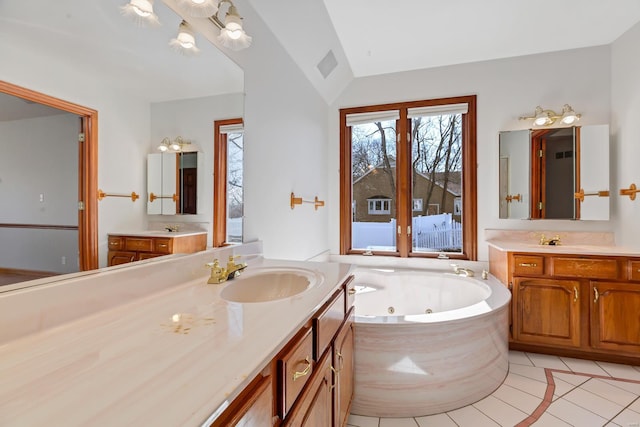 bathroom with visible vents, lofted ceiling, a whirlpool tub, tile patterned floors, and a sink