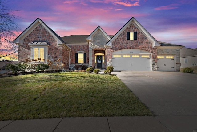 view of front of house featuring an attached garage, brick siding, a yard, concrete driveway, and stone siding