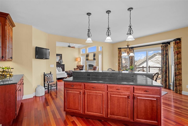 kitchen featuring glass insert cabinets, dark wood-style flooring, hanging light fixtures, dark brown cabinets, and a fireplace