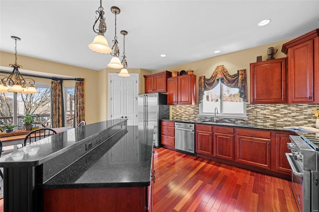 kitchen with decorative backsplash, dark wood-type flooring, stainless steel appliances, dark brown cabinets, and a sink