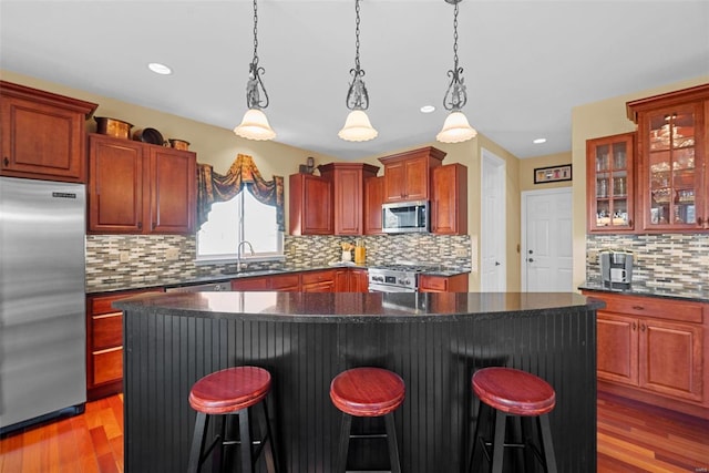 kitchen featuring light wood-style floors, stainless steel appliances, a sink, and a kitchen breakfast bar