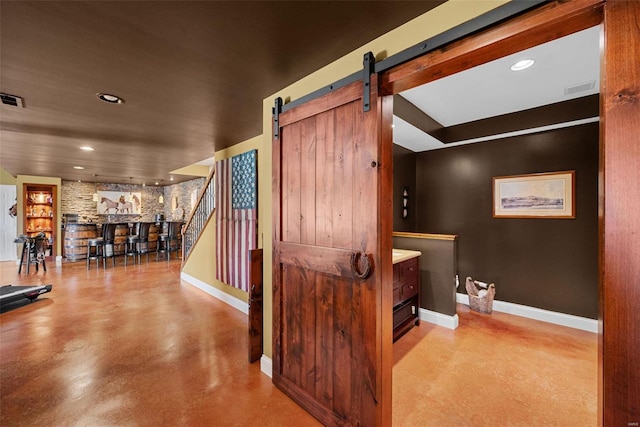 interior space featuring a barn door, finished concrete floors, visible vents, and baseboards