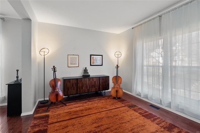 sitting room with wood finished floors, visible vents, and baseboards