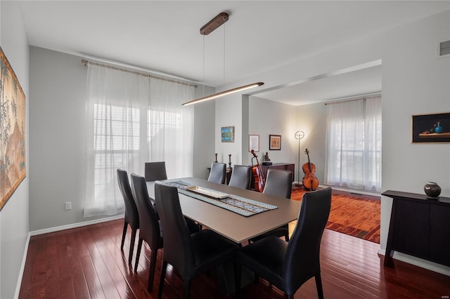 dining space with baseboards, visible vents, and wood-type flooring