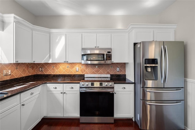 kitchen with dark stone counters, backsplash, appliances with stainless steel finishes, and white cabinets