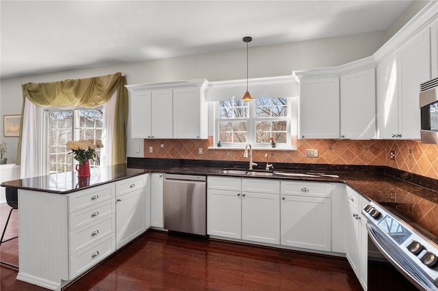 kitchen featuring a sink, a peninsula, appliances with stainless steel finishes, and white cabinets