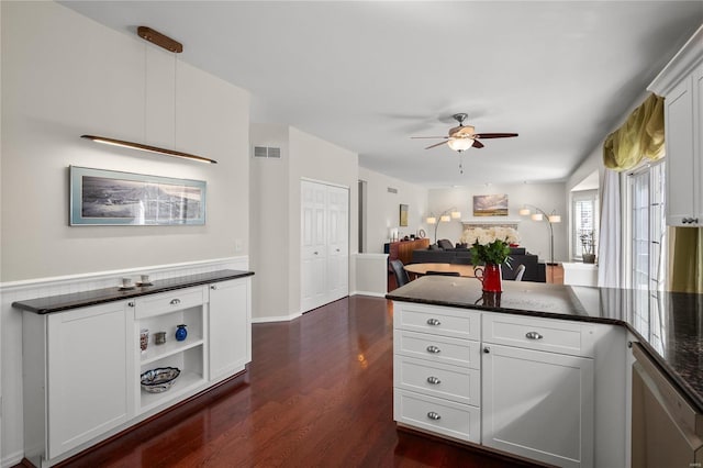 kitchen with visible vents, dark wood finished floors, a peninsula, white cabinets, and ceiling fan