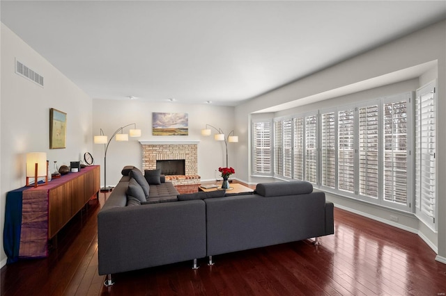 living room featuring hardwood / wood-style flooring, a brick fireplace, baseboards, and visible vents