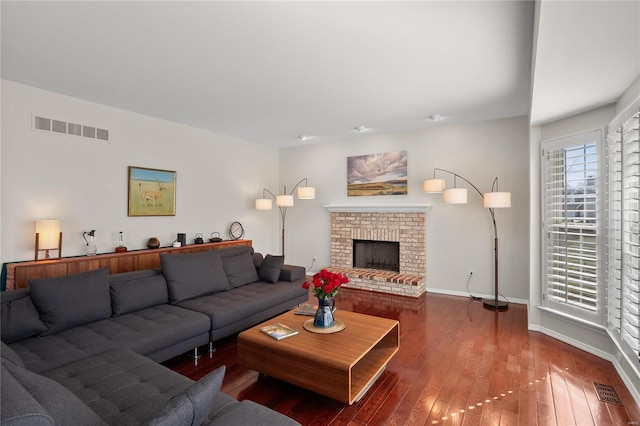 living room featuring hardwood / wood-style floors, baseboards, visible vents, and a fireplace