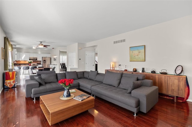 living area with dark wood finished floors, visible vents, and ceiling fan