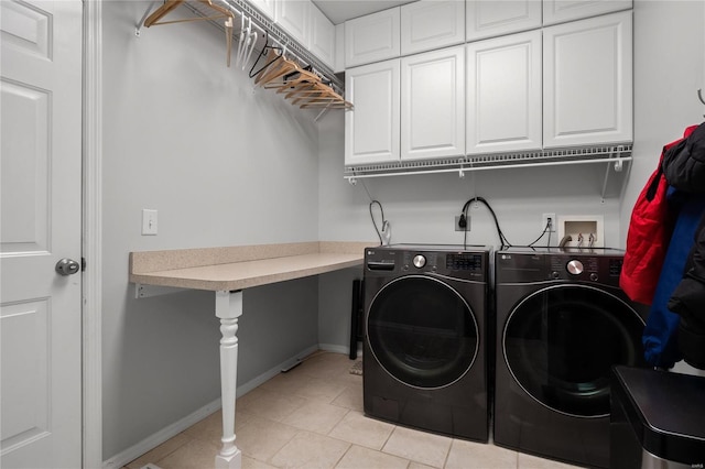 laundry area featuring light tile patterned floors, cabinet space, baseboards, and washer and clothes dryer