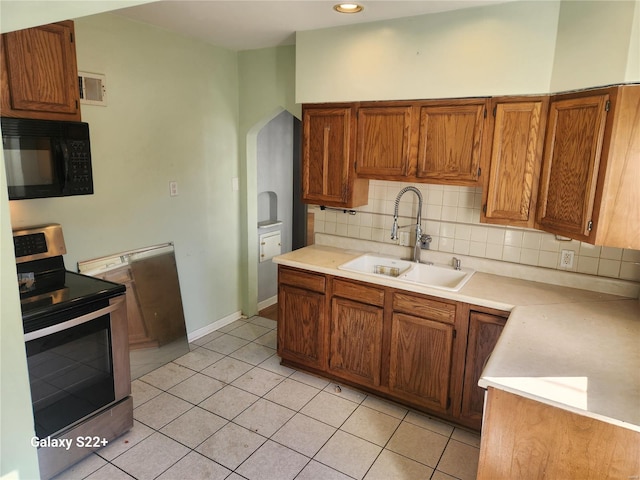 kitchen with brown cabinets, light countertops, stainless steel range with electric cooktop, a sink, and black microwave