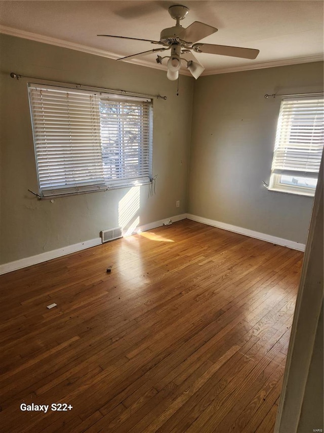 unfurnished room with baseboards, crown molding, visible vents, and wood finished floors