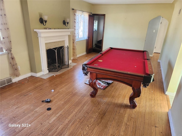 game room with arched walkways, a fireplace with flush hearth, wood finished floors, and visible vents