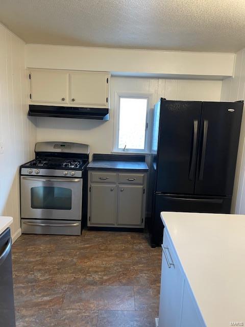 kitchen with appliances with stainless steel finishes, white cabinetry, under cabinet range hood, and a textured ceiling