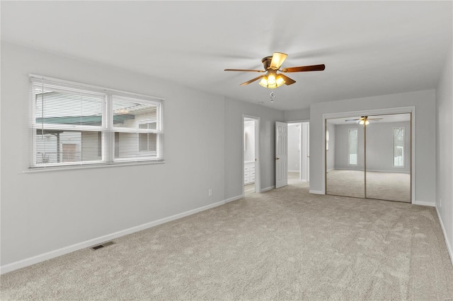 unfurnished bedroom with ceiling fan, light colored carpet, and a closet