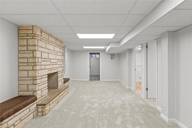 basement with carpet, a drop ceiling, and a fireplace