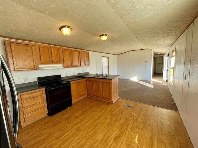 kitchen with black electric range oven, sink, stainless steel fridge, light hardwood / wood-style floors, and kitchen peninsula