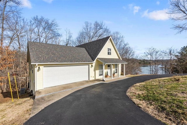 view of front of property with a water view, a garage, and central AC unit