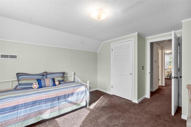 bedroom featuring dark colored carpet, lofted ceiling, a textured ceiling, and a closet