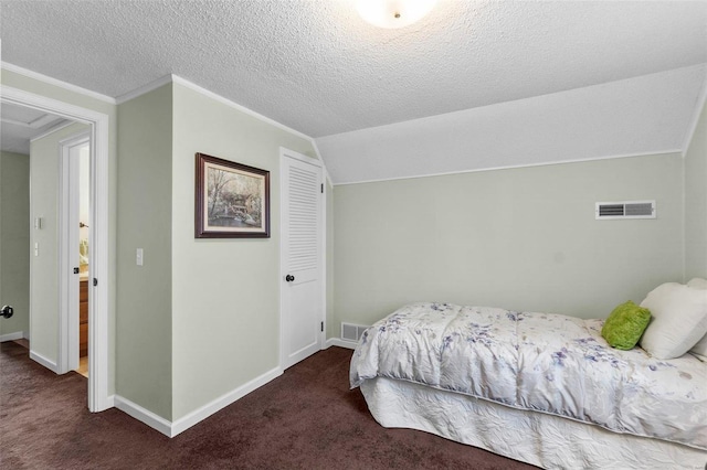 bedroom featuring lofted ceiling, a textured ceiling, and dark carpet