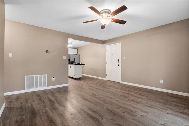 unfurnished living room featuring dark wood-type flooring and ceiling fan