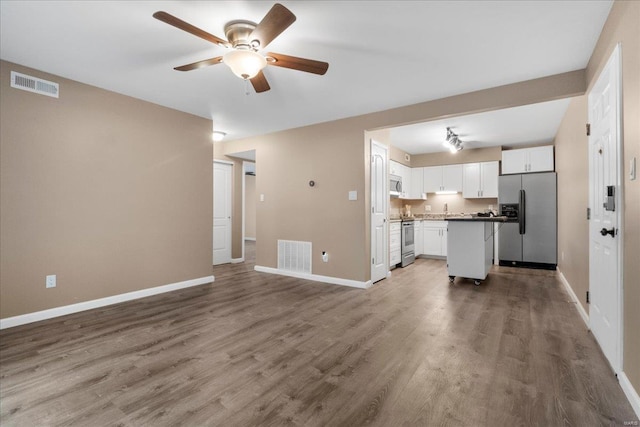 kitchen featuring hardwood / wood-style flooring, ceiling fan, appliances with stainless steel finishes, a center island, and white cabinets