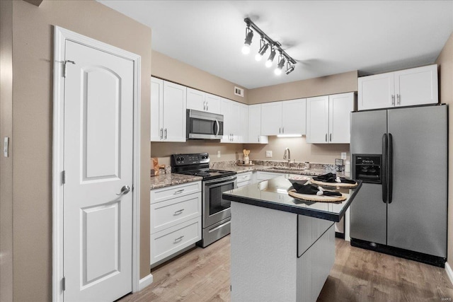 kitchen with white cabinetry, light hardwood / wood-style flooring, stainless steel appliances, and a kitchen island