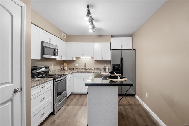 kitchen with white cabinetry, sink, a center island, stainless steel appliances, and light wood-type flooring