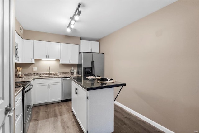 kitchen featuring sink, hardwood / wood-style flooring, stainless steel appliances, a center island, and white cabinets