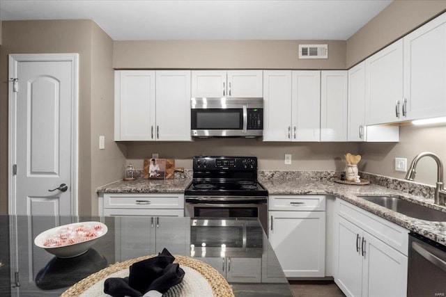 kitchen with appliances with stainless steel finishes, sink, white cabinets, and light stone counters