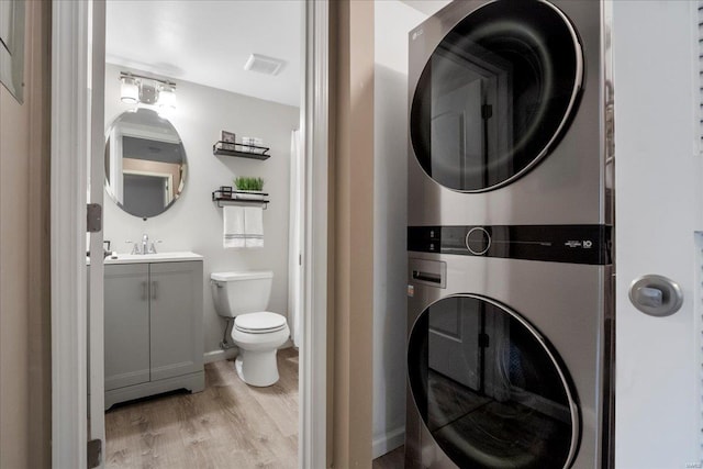 laundry area featuring stacked washer / dryer and light hardwood / wood-style floors