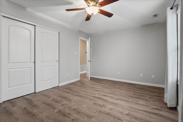 unfurnished bedroom with ceiling fan, light hardwood / wood-style floors, and a closet