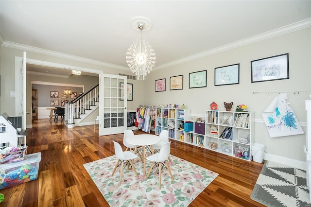 game room with an inviting chandelier, crown molding, wood finished floors, and french doors