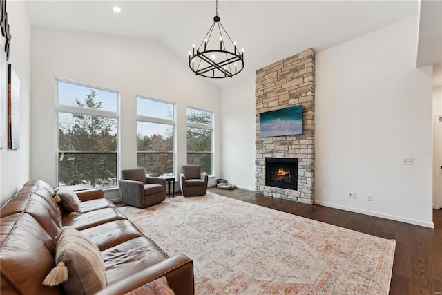 living room featuring dark wood-type flooring, a chandelier, a fireplace, and high vaulted ceiling