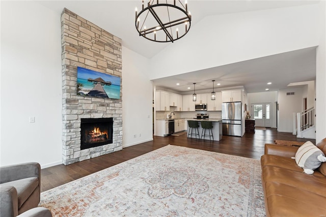 living room with a fireplace, dark hardwood / wood-style flooring, high vaulted ceiling, and a notable chandelier