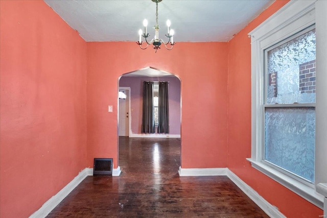 unfurnished dining area featuring an inviting chandelier and dark wood-type flooring